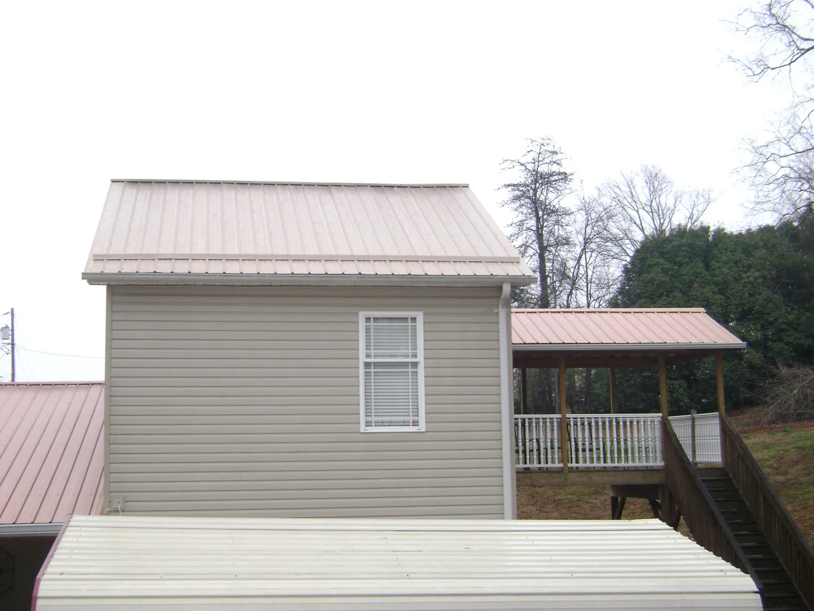 Tan metal roofs on a two story addition and attached porch, from a Roof Replacement job in Yorkville